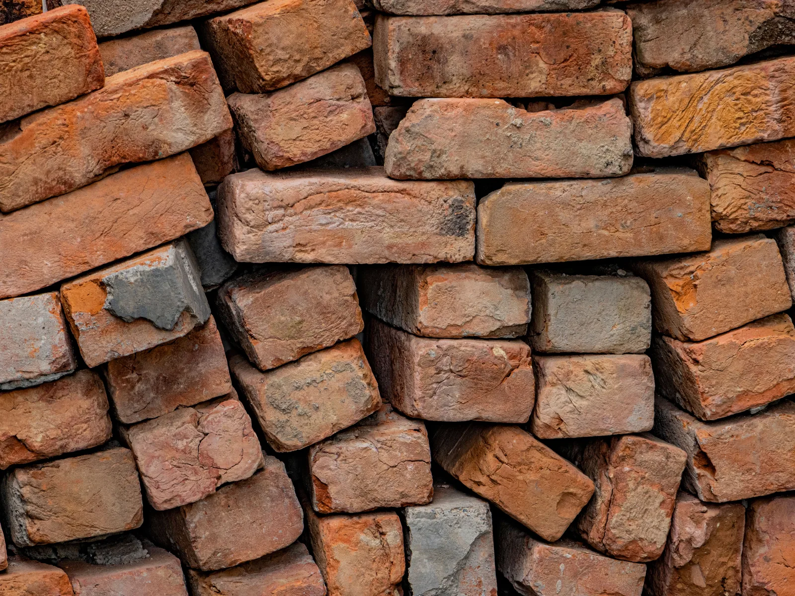 Reclaimed bricks stacked for grading, old mortar still on their faces